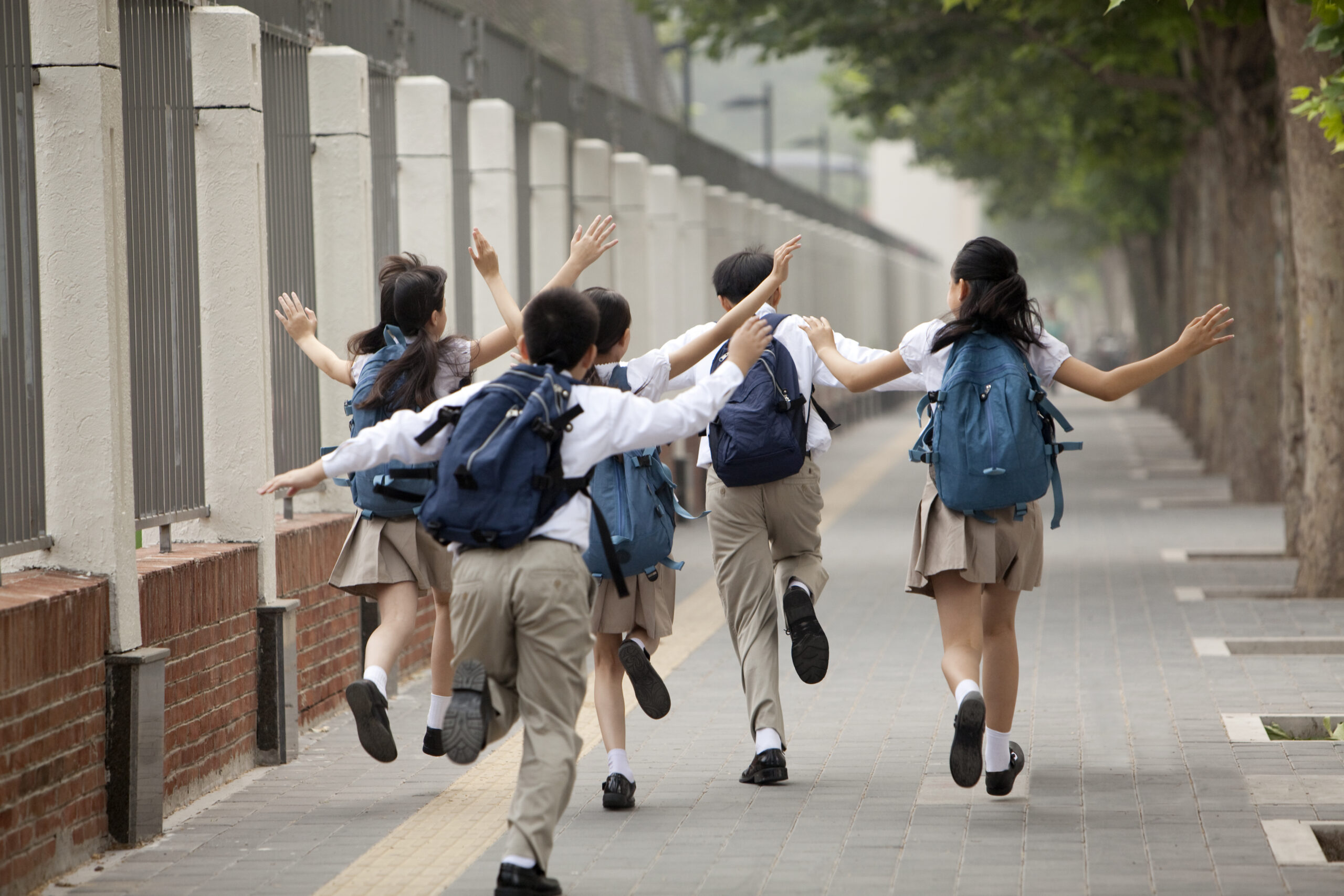 Rear view of lively Chinese schoolchildren in uniform on the way to school